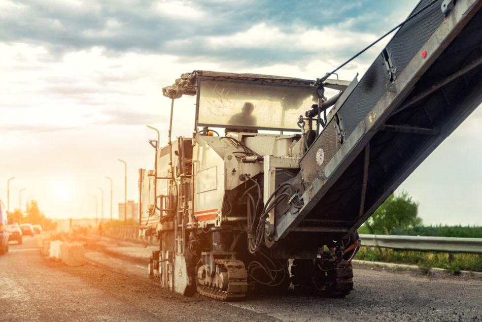 Asphalt milling and grinding machine at road repair and construction site. Highway renewal with heavy machinery.