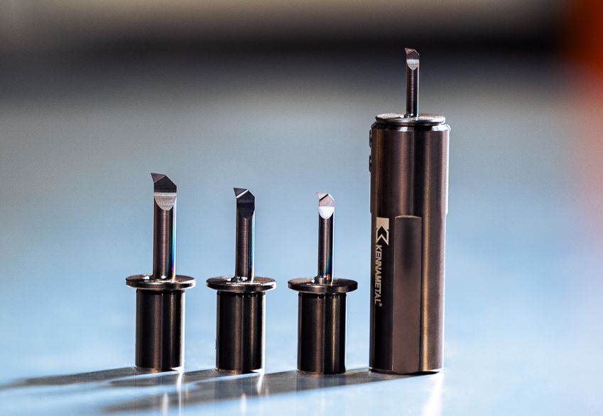 Four Kennametal TopSwiss MBS inserts in sleeves and a tool holder