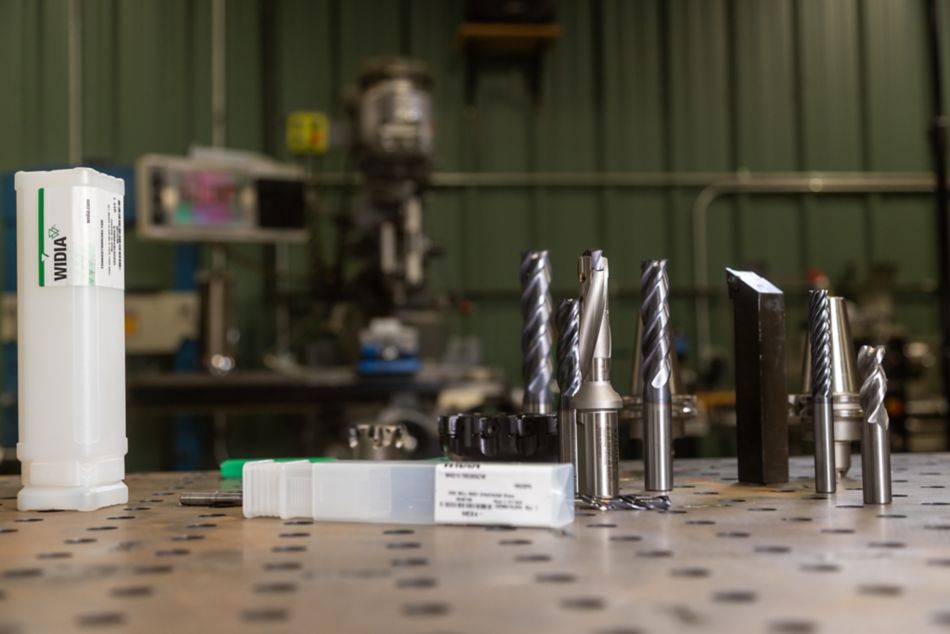 Group of WIDIA metal cutting tools including indexable mills, solid end mills, tool holders, turning tools, drills, and product packaging