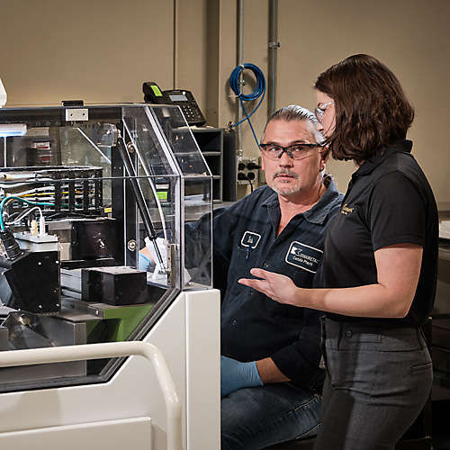 Two Kennametal employees with an additive manufacturing machine