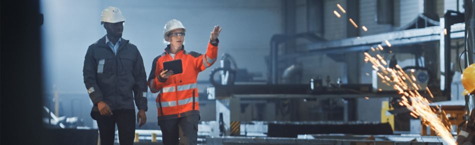 Man and Woman in PPE Walking Through a Steel Factory Banner