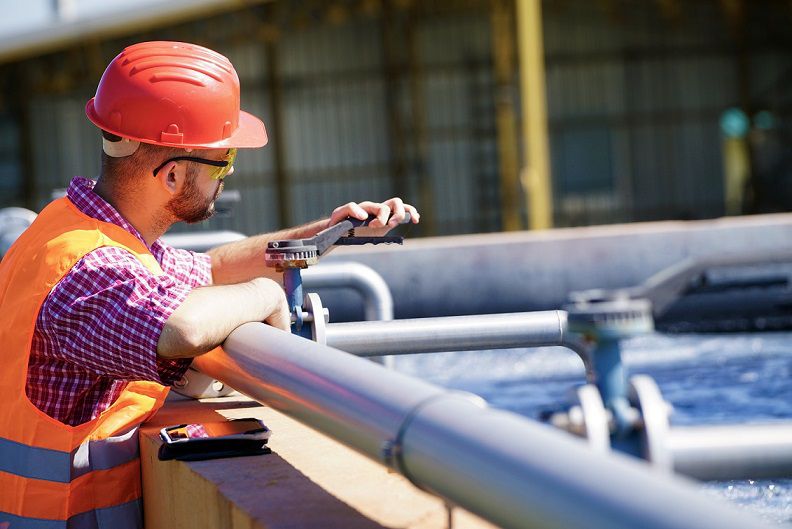 Man Wearing Hard Hat Working on Pipes