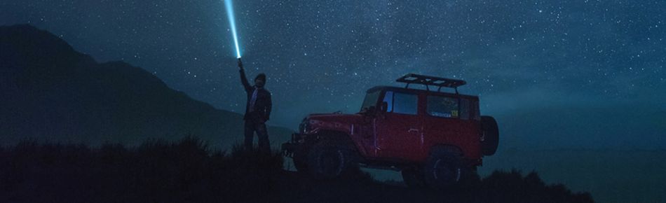 Man with Car, Holding Light to Sky at Night Banner