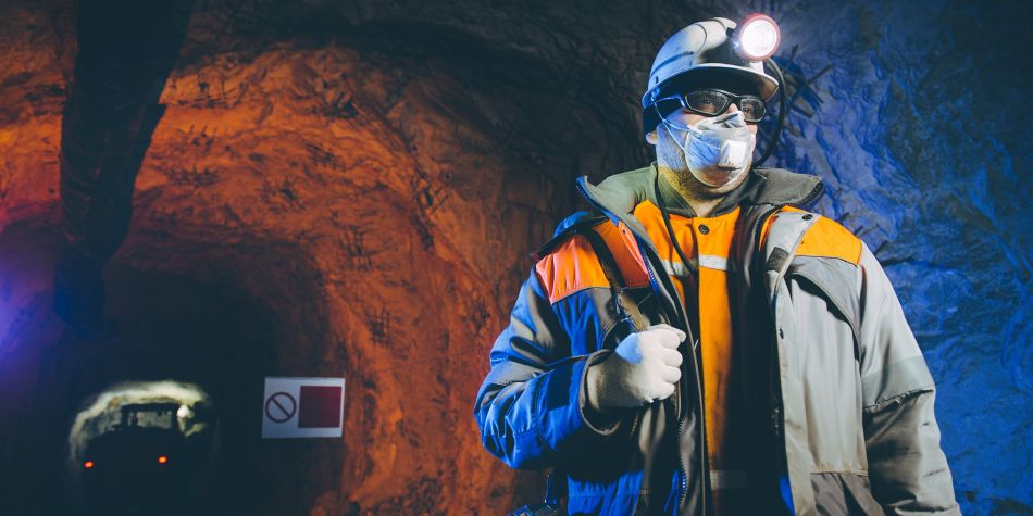 Miner underground wearing PPE hard hat, goggles, mask, gloves