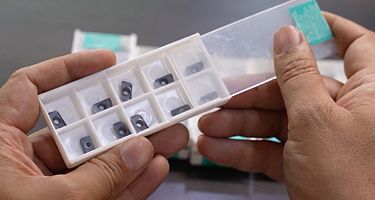 Hands holding a pack of Metal Removal by WIDIA Inserts