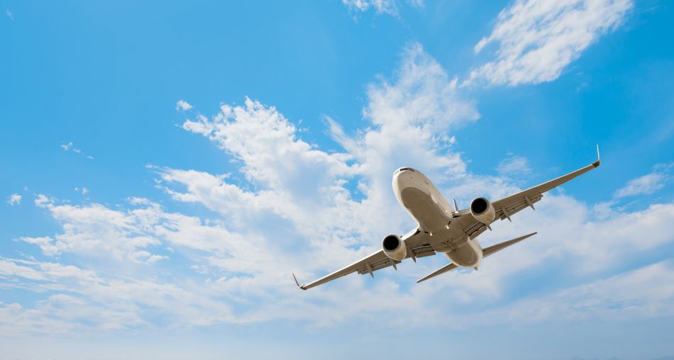 White passenger airplane flying in the sky with clouds