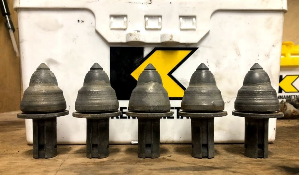 Five Road King PCD teeth lined up against a Kennametal box