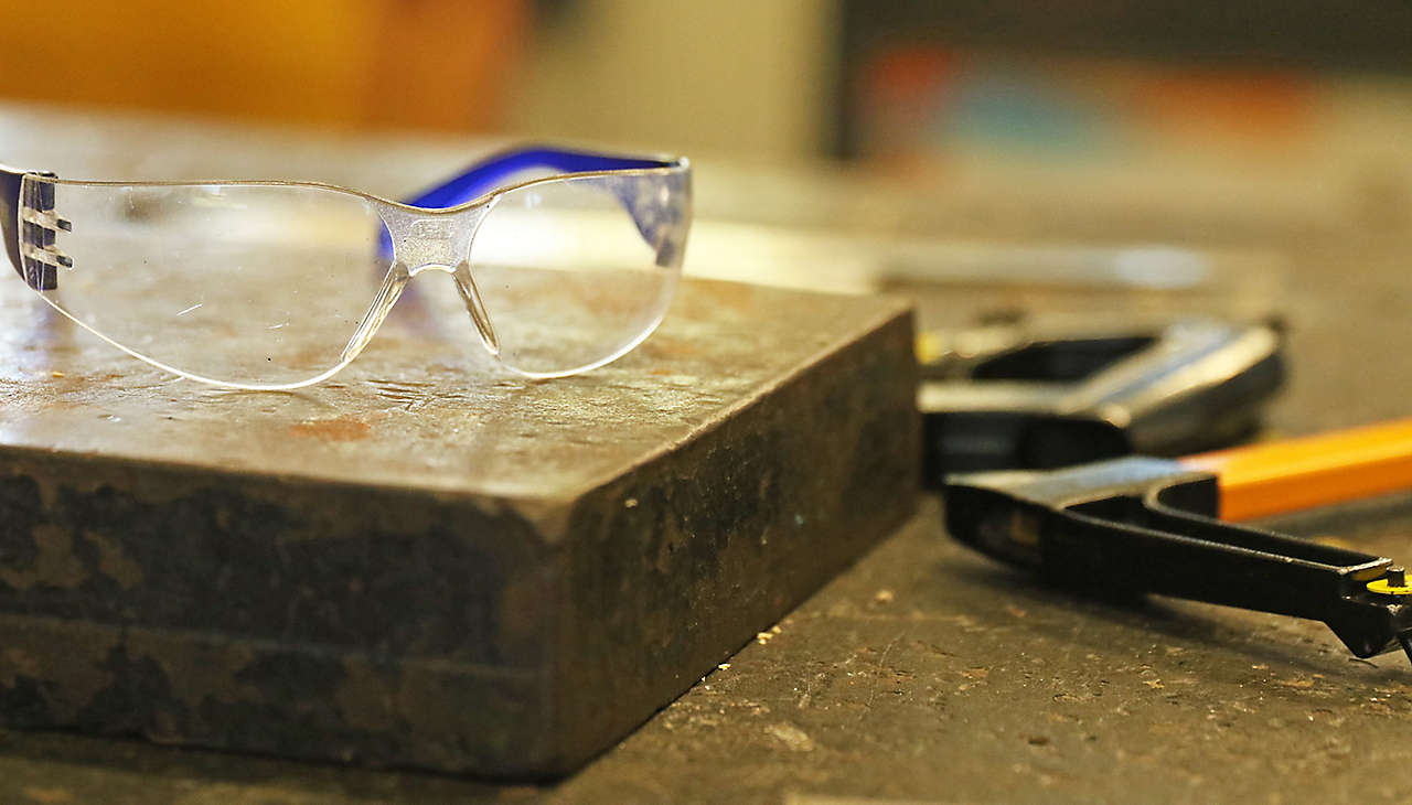 Safety goggles in the industrial technology workshop  with tools. Factory trade concept personal health safety in the workshop. Down tools. metal sheet worker. 