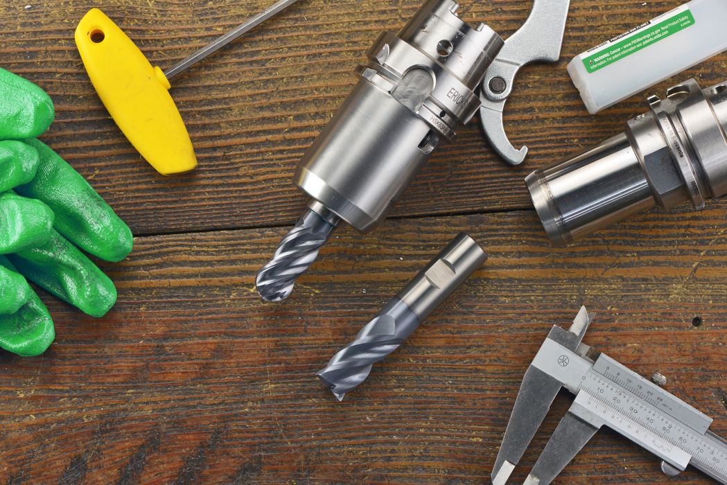 WIDIA WCE4 and WCE4 ball-nose solid end mills on a wood table surrounded by green gloves, milling tool holders, and other tools