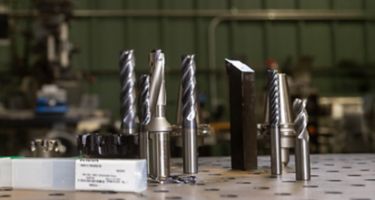 Group of WIDIA tooling including solid end mills, drills, turning tools, indexable mills, and packaging